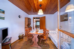 Un coin repas avec une table en bois, des chaises et un téléviseur posé sur un meuble.