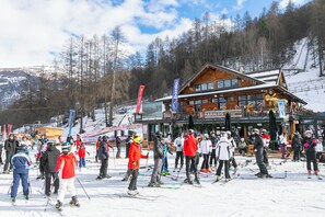 Ein Skigebiet mit einer Holzhütte, Skipisten und einer Menschenmenge von Skifahrern.