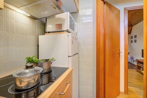 A compact kitchen with a refrigerator, stove, and cabinets. - La Tana dello Scoiattolo (Skiing nearby) (Bardonecchia)