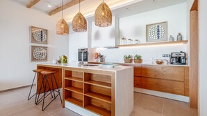 Una cocina moderna con una isla central, iluminación colgante y armarios de madera.