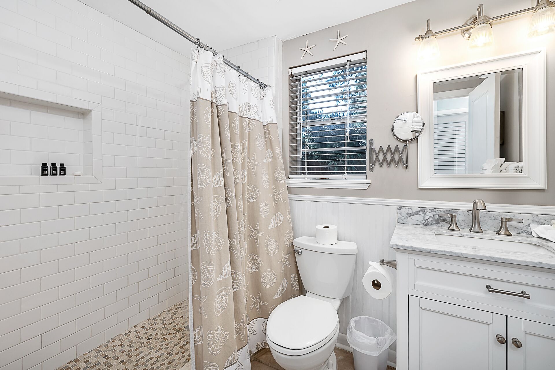 A bathroom with a shower curtain, toilet, sink, and mirror.