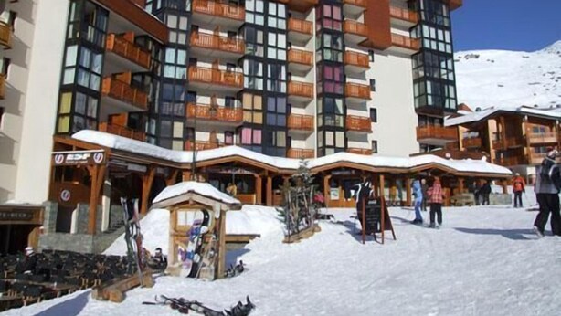 A multi-story hotel with balconies, ski equipment, and a snowy ground. - 50m from ski slopes, 2nd floor, balcony, tv, 35m², Val Thorens (Val Thorens)