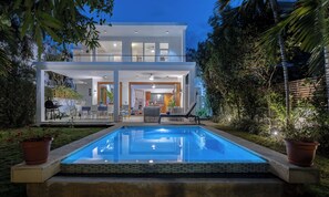 Une maison moderne à deux étages dotée d’une piscine, d’un espace extérieur aménagé et d’un coin barbecue.