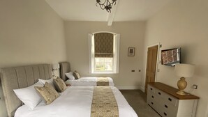 A bedroom with a large bed, a dresser, a mirror, and a window with a view. - Red Barns Bed & Breakfast (Redcar)