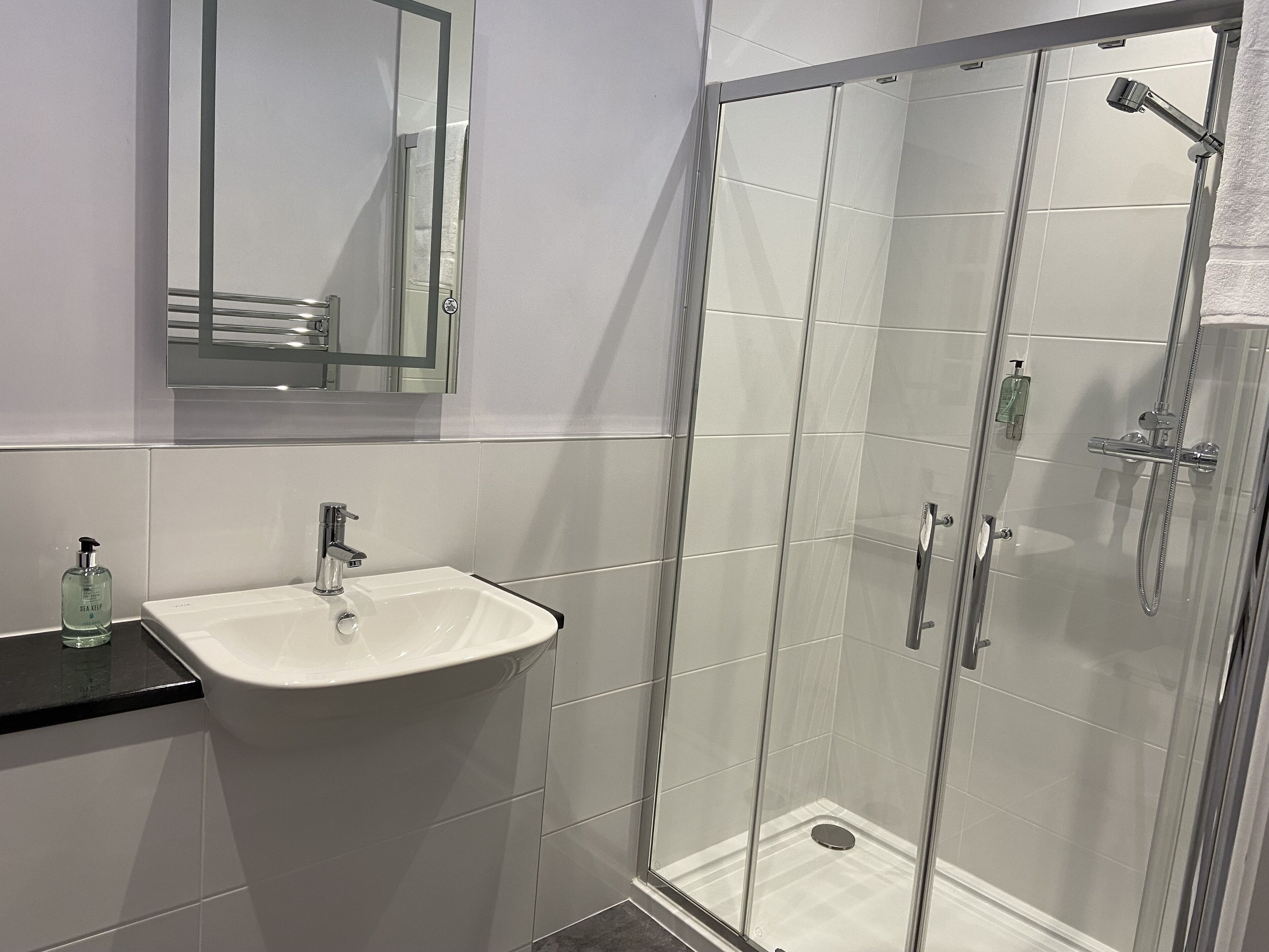 A bathroom with a white sink, a mirror, and a glass-enclosed shower area.