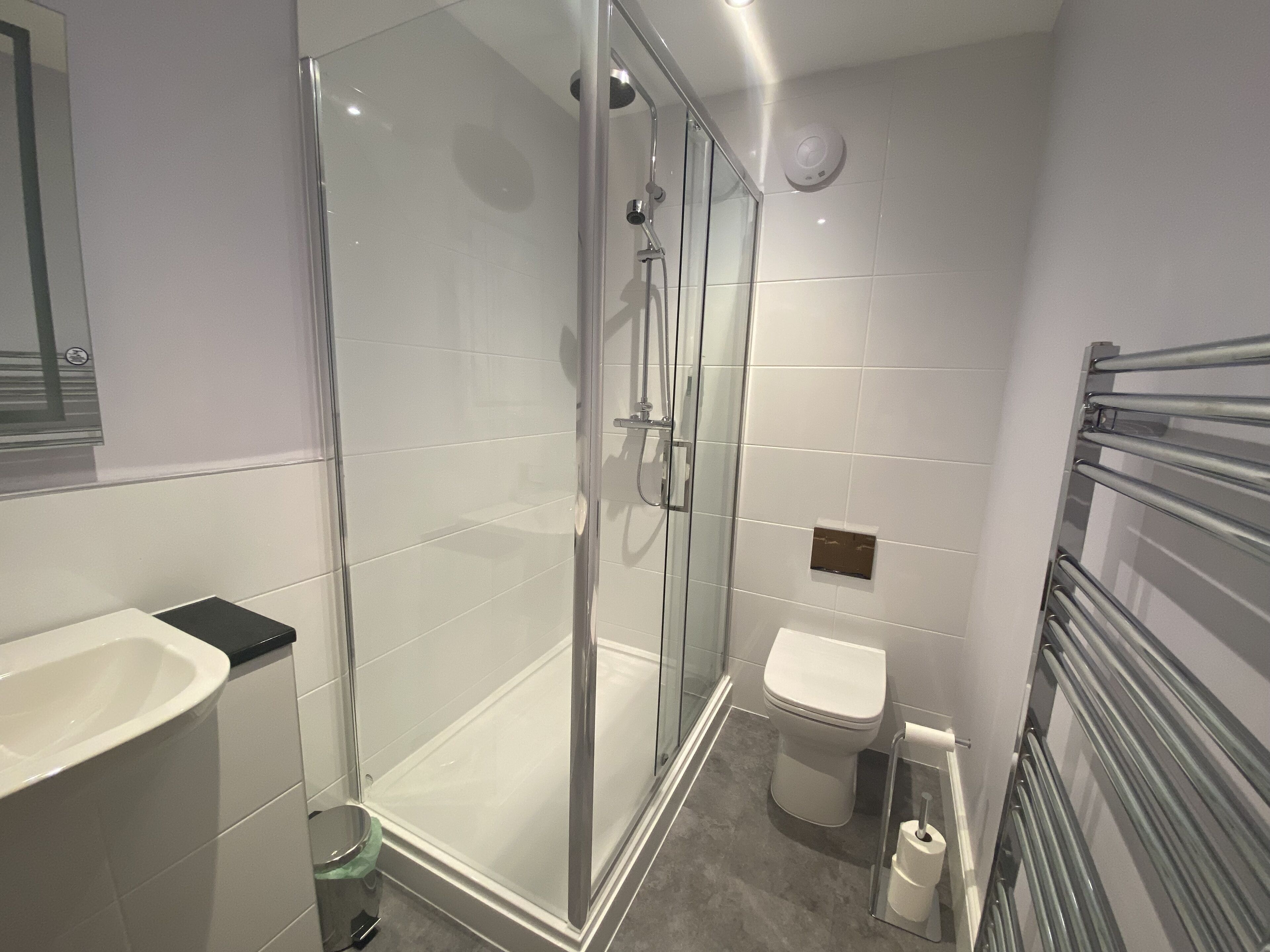 A modern bathroom with a glass-enclosed shower, a white sink, and a toilet.