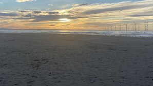 A beach with a sunset and wind turbines in the distance. - Red Barns Bed & Breakfast (Redcar)
