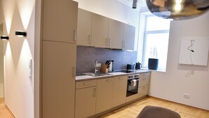 Et moderne køkken med beige skabe, indbygget ovn og et vindue med naturligt lys.