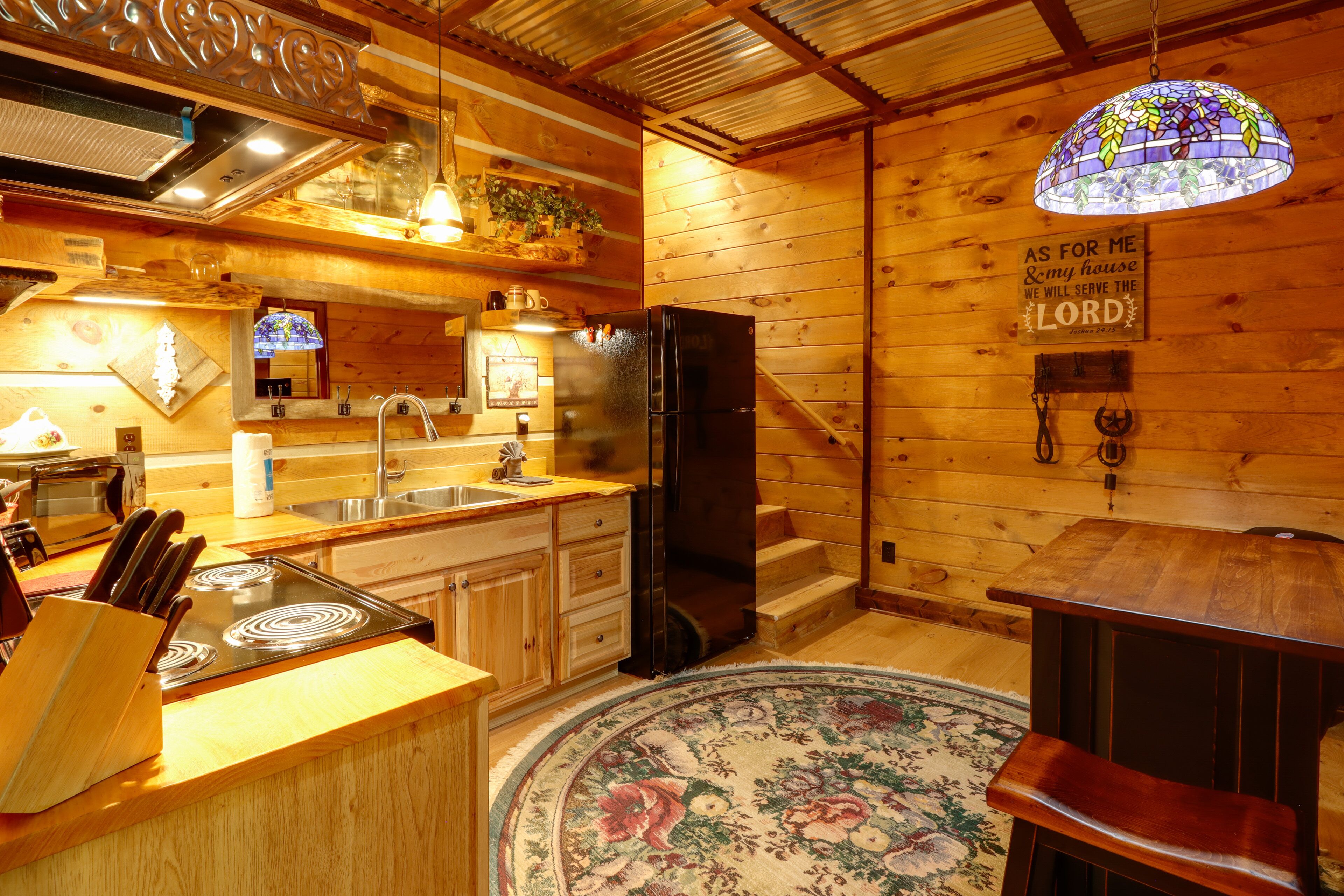 Eine Holzhütte mit einer Küche, inklusive Kühlschrank, Herd, Spüle und Holzausbau.