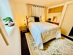 Une chambre à coucher bien rangée, avec un lit, une table de chevet, une lampe et une petite plante en pot.