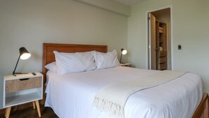 A neatly made bed with white bedding and a wooden headboard, flanked by bedside tables with lamps. - w* | Remarkable 1BR with Balcony in Miraflores (Miraflores)