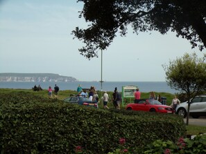 A coastal area with people, a red car, and a signboard. - 4thedome (New Milton)