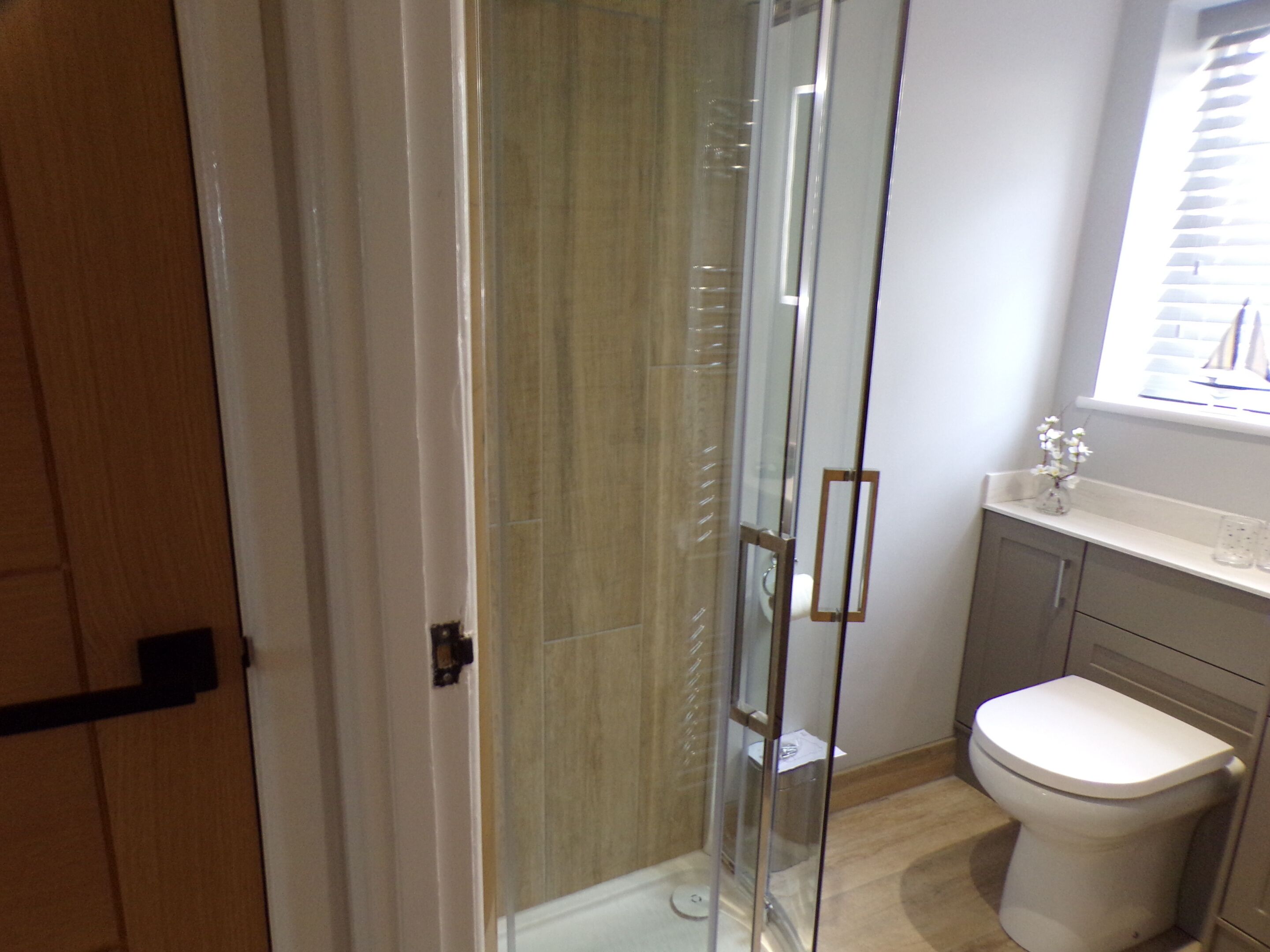 Une salle de bain moderne avec une douche à parois de verre, des toilettes et un meuble-lavabo avec une fenêtre au-dessus du lavabo.