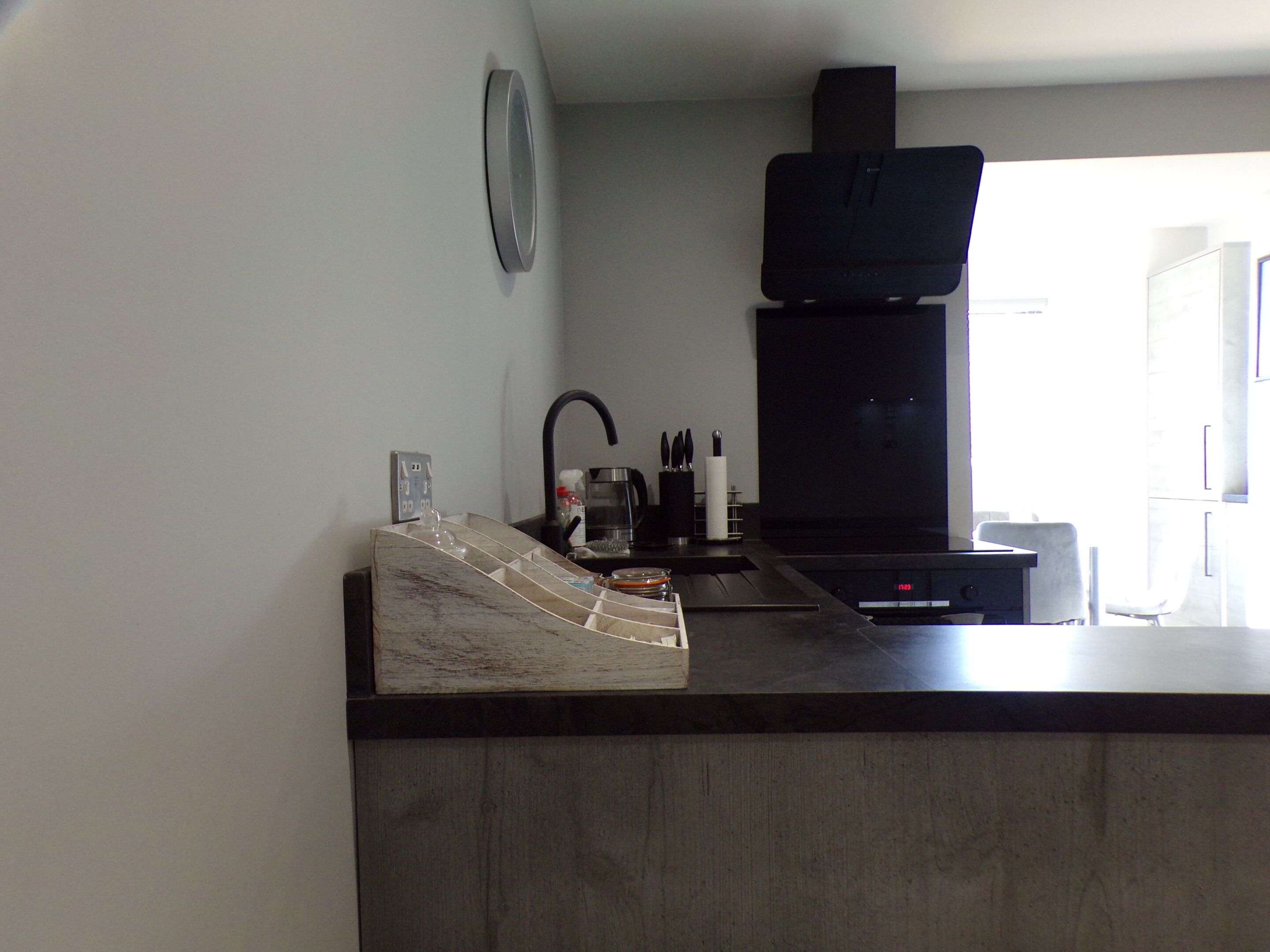A modern kitchen with a black stove, a sink, and a countertop with a glass container and utensils.