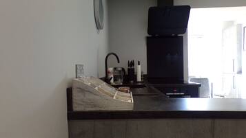 A modern kitchen with a black stove, a sink, and a countertop with a glass container and utensils.