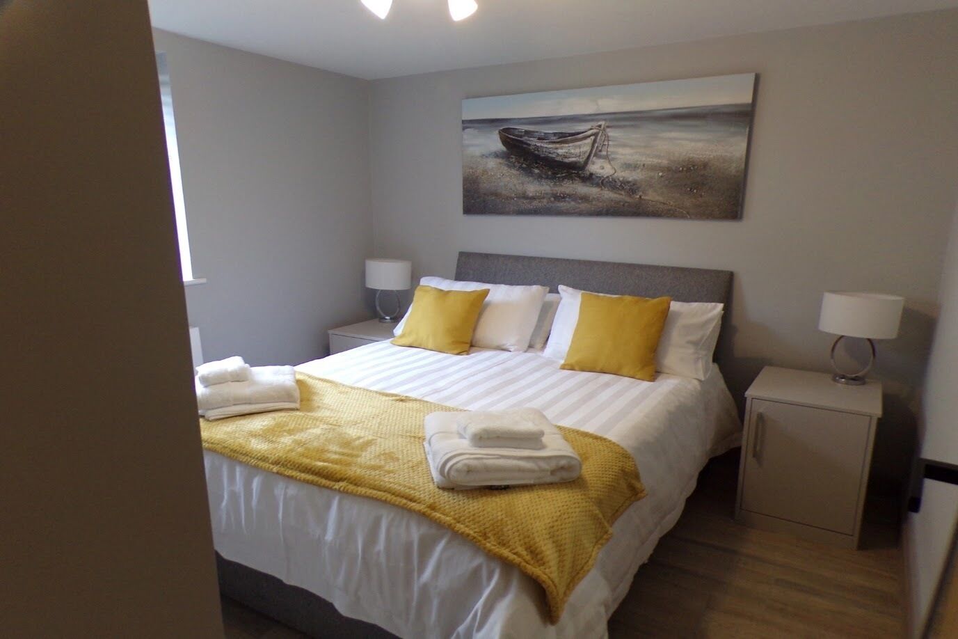 Una habitación de hotel con una cama, dos mesitas de noche, un cuadro y una ventana.