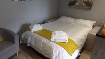 Een hotelkamer met een bed, een stoel en een schilderij aan de muur.