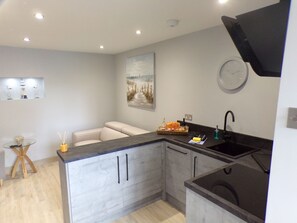 A modern kitchen with a built-in island, a sink, and a clock on the wall. - 4thedome (New Milton)
