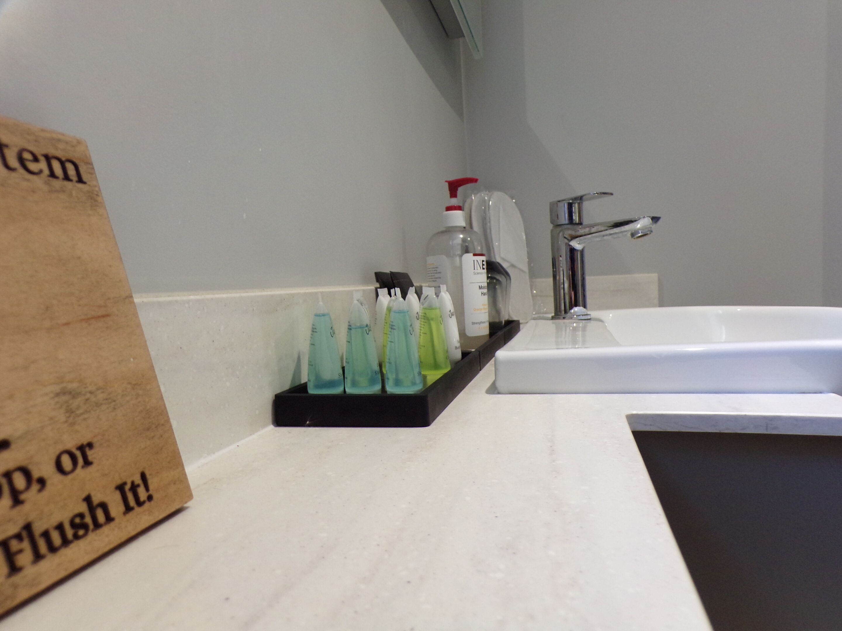 Une salle de bain avec un lavabo blanc, un miroir et une étagère contenant divers produits de toilette.