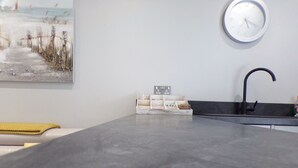 Une cuisine moderne avec un plan de travail gris, un robinet noir et une horloge au mur.