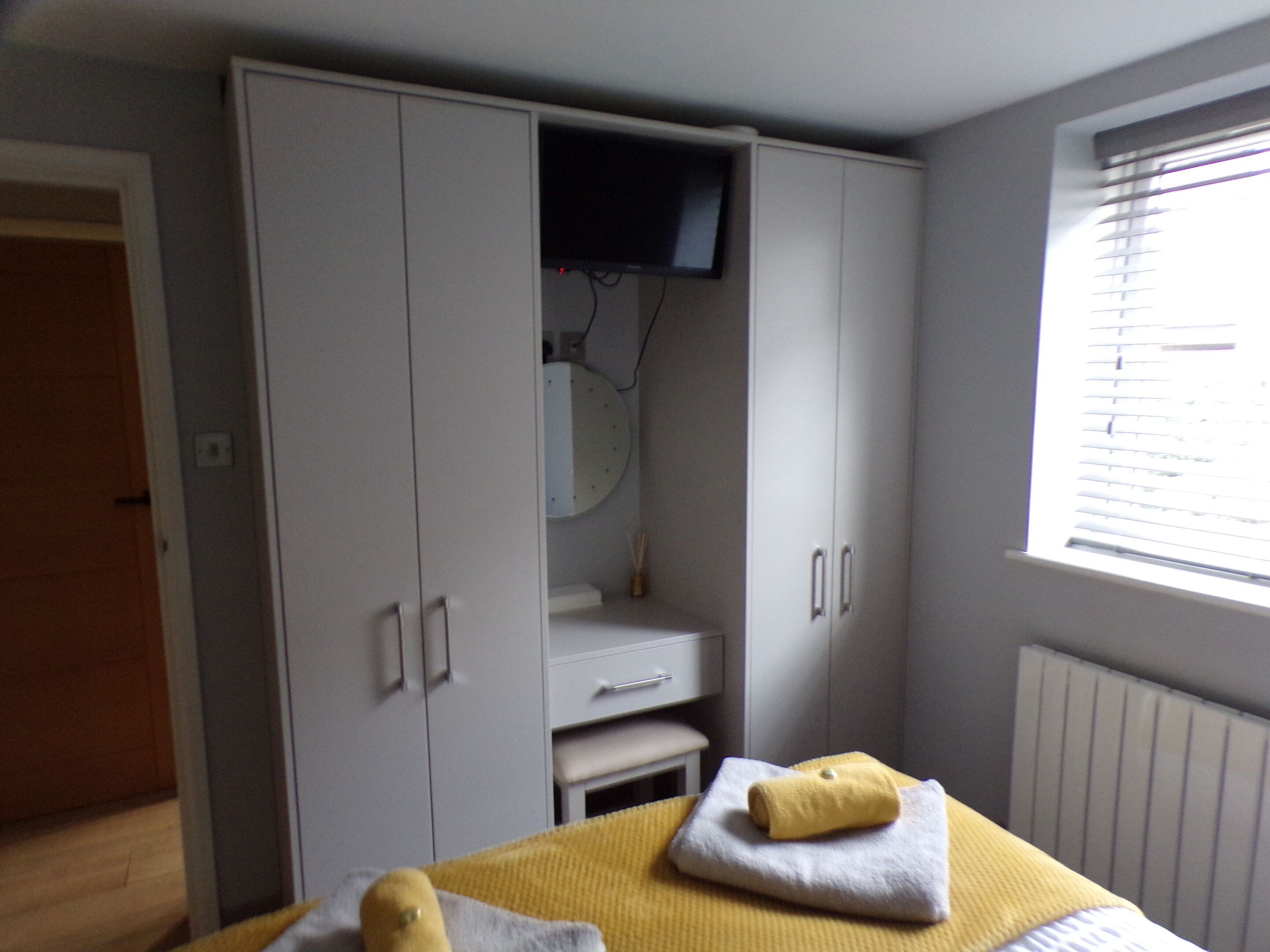A bedroom with a bed, a wardrobe, a television, and a window.
