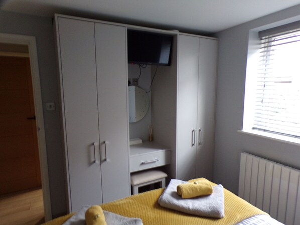A bedroom with a bed, a wardrobe, a television, and a window. - 4thedome (New Milton)