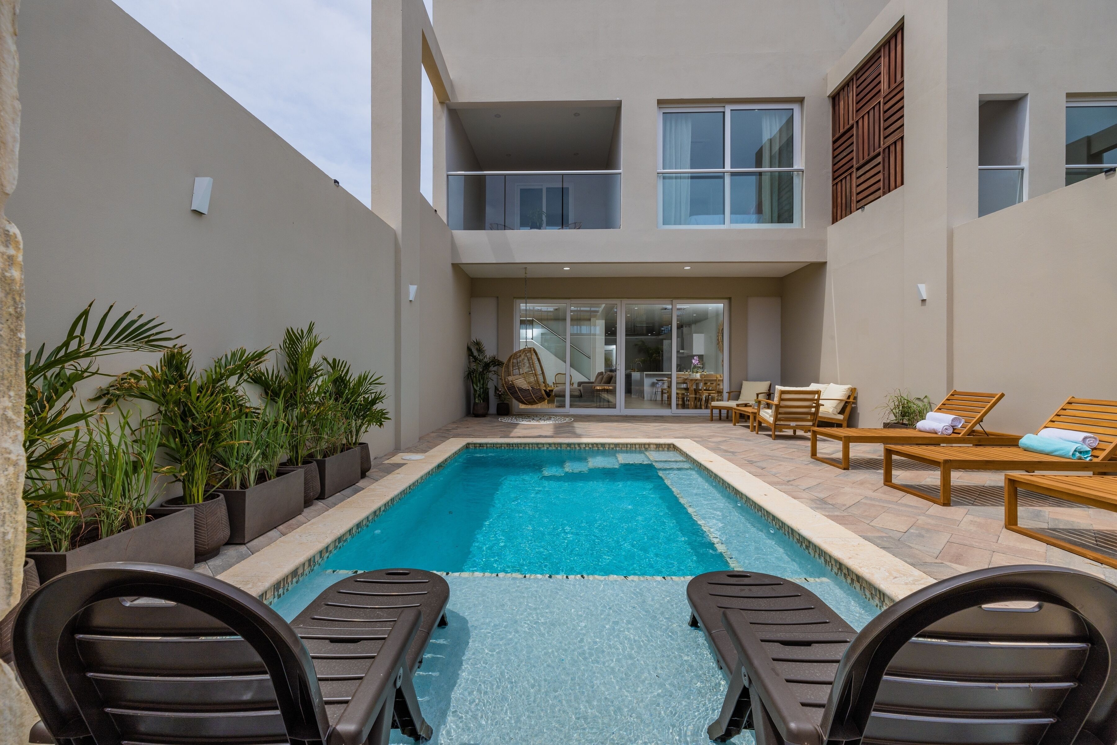A modern pool area with lounge chairs and a glass door entrance.
