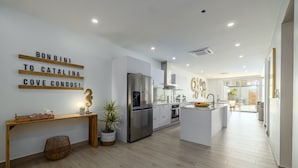 Una cocina moderna con refrigerador de acero inoxidable, piso de madera e isla central.