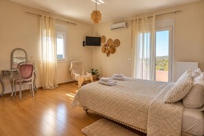 Une chambre à coucher avec un lit, une chaise, une télévision et une vue sur l’extérieur.