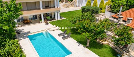 A residential property with a swimming pool, outdoor seating, and a garden.