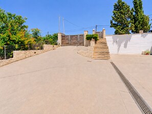 A paved driveway leading to a gated entrance with a staircase.