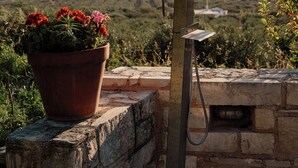 A showerhead attached to a stone wall with a potted plant nearby. - Blue Sky Villa in Crete (Επάνω Βαθειά)