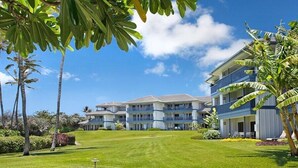 A hotel with multiple floors, a well-maintained lawn, and palm trees. - Poipu Sands 124 Steps to Shipwreck Beach By Suite Paradise (Koloa)