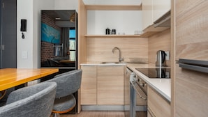 A compact kitchen with a wooden countertop, a built-in oven, and a sink. There are two grey chairs and a wooden dining table. - Matrix 504 (Cape Town)