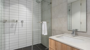 A modern bathroom with a glass-enclosed shower, a white sink with a wooden vanity, and a large mirror. - Matrix 504 (Cape Town)