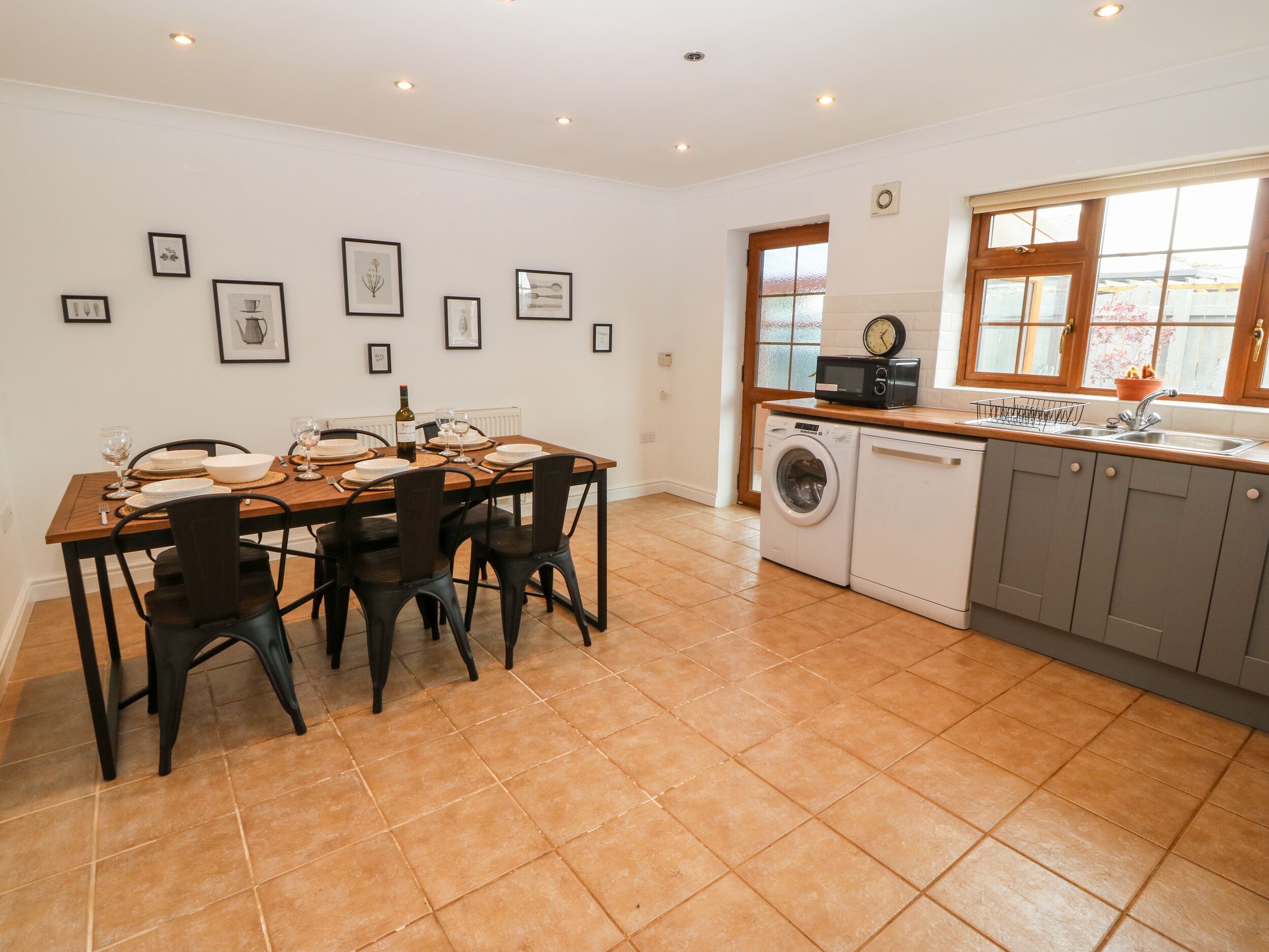 A modern kitchen with a dining area, featuring a washing machine, a microwave, and a sink.