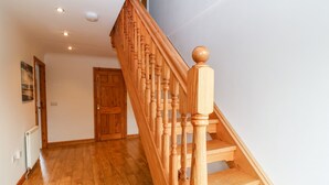 Eine Holztreppe mit Handlauf, einer Holztür und einem Heizkörper an der Wand.