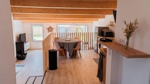 Eine moderne Küche mit Holzbalken, einem Essbereich mit rundem Tisch und Blick ins Freie.