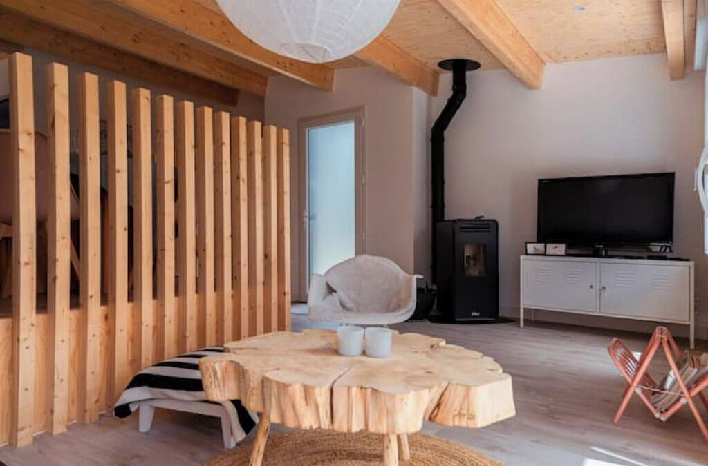 A cozy room with a wooden slat wall, a round wooden table with two chairs, a television, and a cabinet.