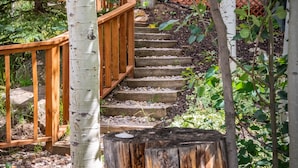 A wooden staircase with a wooden railing, surrounded by trees and greenery.