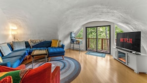 A cozy living room with a blue sofa, a coffee table, and a TV displaying "NETFLIX".