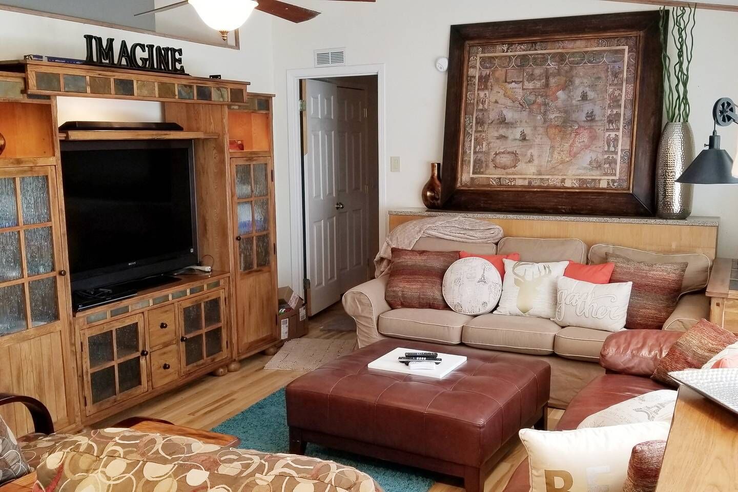 Una sala de estar con televisor, armarios de madera, un sofá y un mapa en la pared.