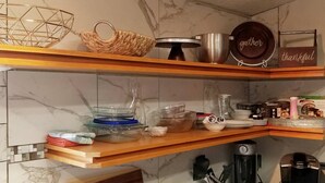 Eine Küche mit Marmorarbeitsplatten, Holzregalen und verschiedenen Küchenutensilien, darunter eine Kaffeemaschine, ein Wasserkocher und eine Kaffeemühle.