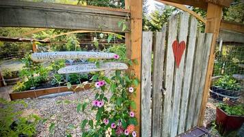 A wooden gate with a heart-shaped decoration, surrounded by a garden with various plants and flowers.