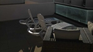A rooftop terrace with a glass enclosure, white chairs, and a small table. - El Cotillo Sonando,Couples only, Romantic,Minutes from swim/surf,Well equipped. (El Cotillo)