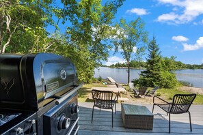 Relax on the deck with a clear view of the tranquil lake and lush greenery, perfect for outdoor cooking and leisurely days.