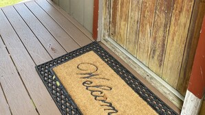 Une porte en bois avec un paillasson sur lequel est écrit « Bienvenue ».