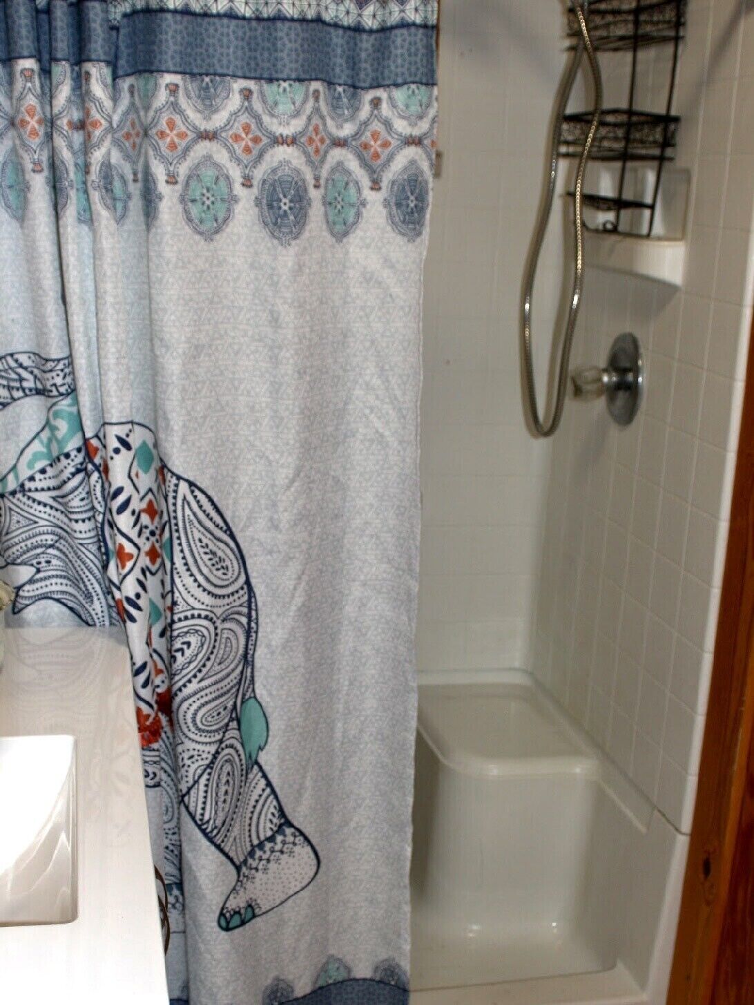 A bathroom with a shower curtain featuring a paisley pattern, a white bathtub, and a metal shower head.