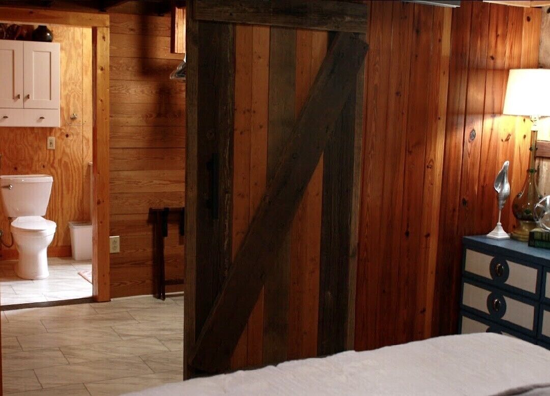 Ein Holzinterieur mit einem Bett, einem Schminktisch und einem Badezimmer mit Toilette und Schrank.