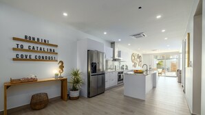 Une cuisine moderne dotée d’un réfrigérateur en acier inoxydable, d’un plancher en bois et d’un îlot central.